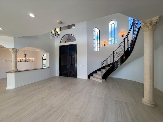 entryway with decorative columns, arched walkways, baseboards, stairway, and a chandelier