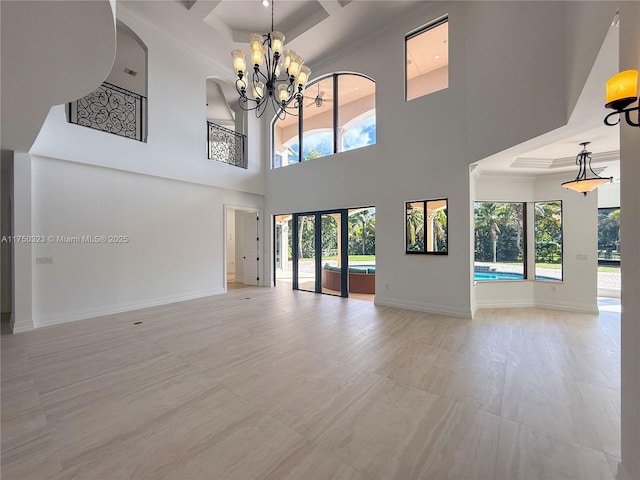 unfurnished living room with a healthy amount of sunlight, crown molding, baseboards, and a notable chandelier