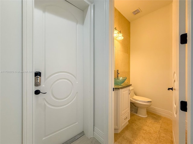 bathroom with toilet, visible vents, baseboards, vanity, and tile patterned floors