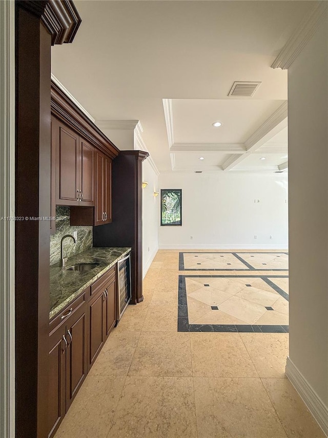 kitchen featuring visible vents, crown molding, baseboards, and a sink