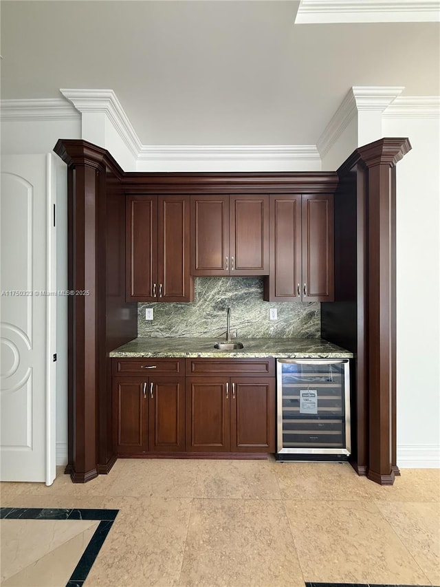 bar with wine cooler, a sink, ornamental molding, tasteful backsplash, and decorative columns