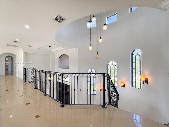 hall featuring an upstairs landing, visible vents, arched walkways, and recessed lighting