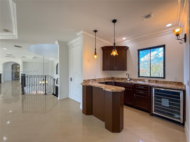 interior space featuring wine cooler, a sink, visible vents, and decorative light fixtures