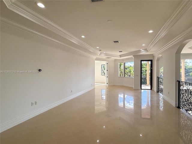 empty room with plenty of natural light, arched walkways, a raised ceiling, and baseboards