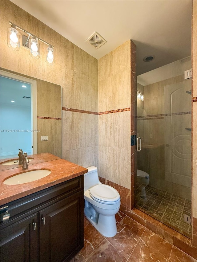 full bathroom featuring tile walls, visible vents, toilet, a shower stall, and vanity