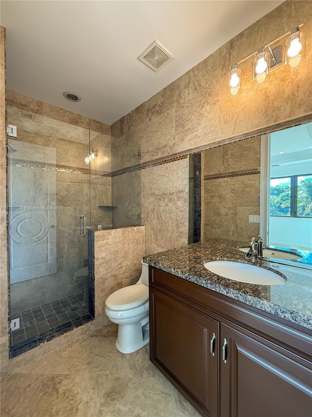 bathroom featuring toilet, vanity, visible vents, tile walls, and a stall shower