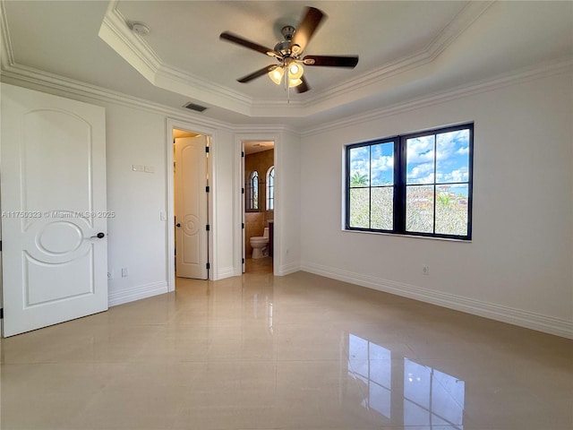 unfurnished bedroom with baseboards, visible vents, ensuite bath, a tray ceiling, and crown molding