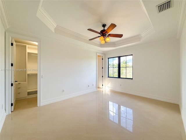 unfurnished bedroom featuring a ceiling fan, visible vents, baseboards, ornamental molding, and a raised ceiling