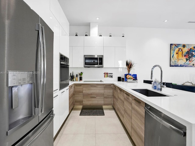 kitchen with light tile patterned floors, stainless steel appliances, white cabinetry, a sink, and modern cabinets