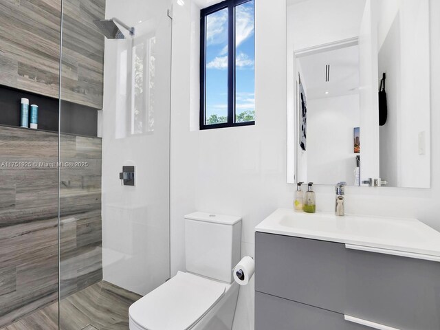 full bathroom with vanity, walk in shower, and toilet