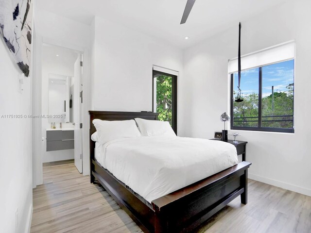 bedroom with light wood-type flooring, ensuite bath, a ceiling fan, and baseboards