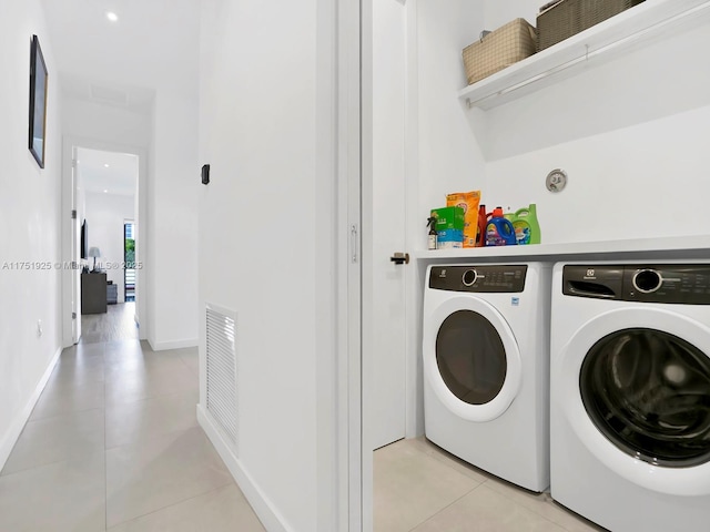 washroom featuring light tile patterned flooring, laundry area, visible vents, baseboards, and washer and dryer