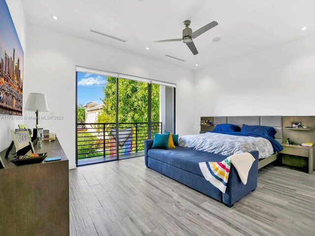 bedroom with wood finished floors, visible vents, and access to exterior