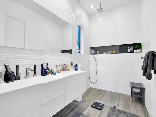 interior space featuring light wood-style flooring, a sink, visible vents, and tile walls