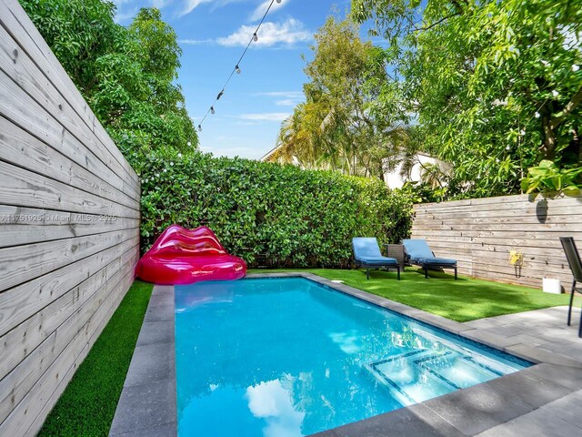 view of pool with a fenced backyard, a patio, and a lawn