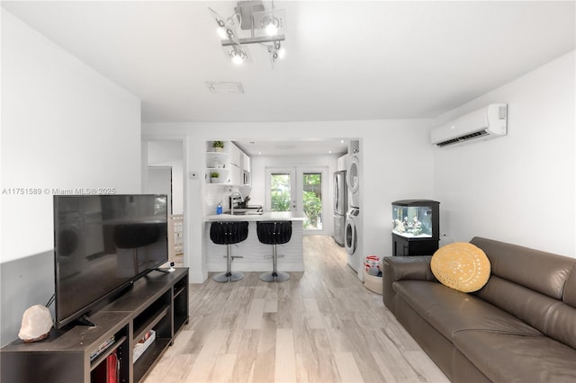 living room featuring light wood-style floors, stacked washer / drying machine, french doors, and a wall mounted AC