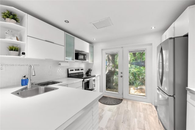 kitchen with light countertops, appliances with stainless steel finishes, a sink, and white cabinets