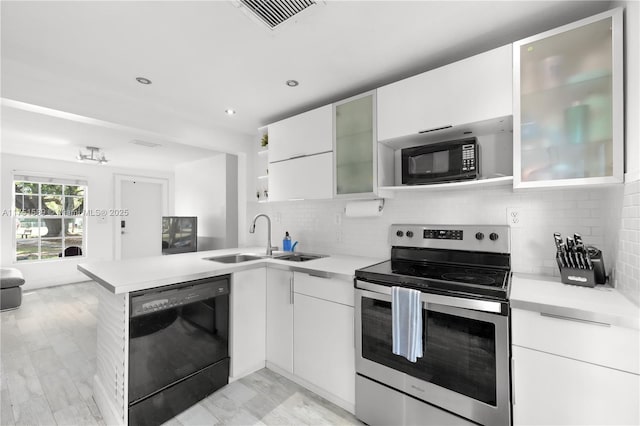 kitchen featuring a peninsula, a sink, visible vents, light countertops, and black appliances