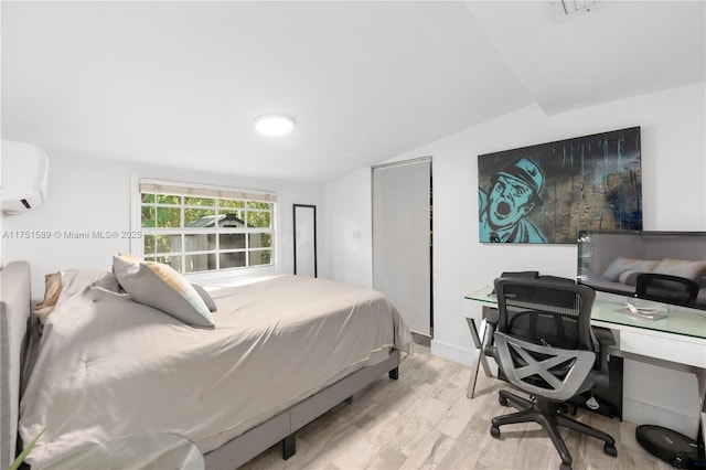 bedroom featuring vaulted ceiling, an AC wall unit, and wood finished floors