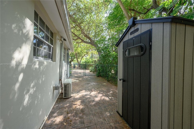 exterior space featuring a patio, an outbuilding, a gate, a storage unit, and fence