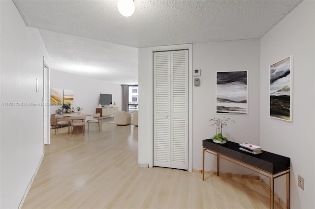 corridor featuring wood finished floors, baseboards, and a textured ceiling