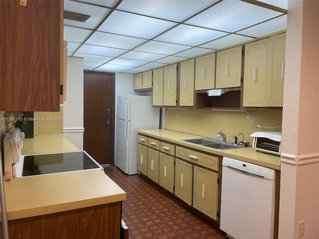 kitchen featuring white appliances, dark floors, cream cabinets, light countertops, and a sink