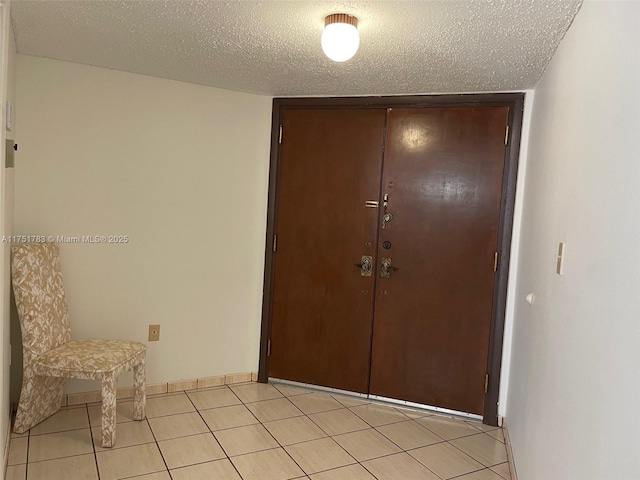 interior space featuring light tile patterned flooring, a textured ceiling, and baseboards