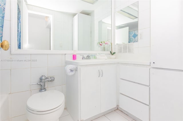 full bathroom with toilet, tile patterned floors, tile walls, and vanity