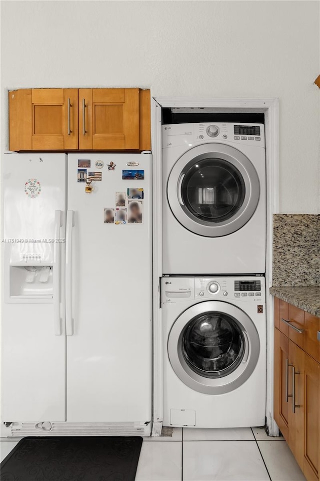 washroom with light tile patterned floors, laundry area, and stacked washer and clothes dryer