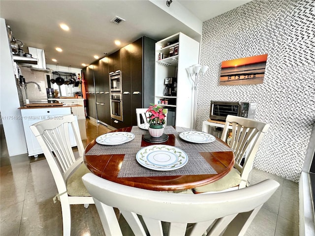 dining room featuring visible vents, concrete floors, a toaster, recessed lighting, and an accent wall