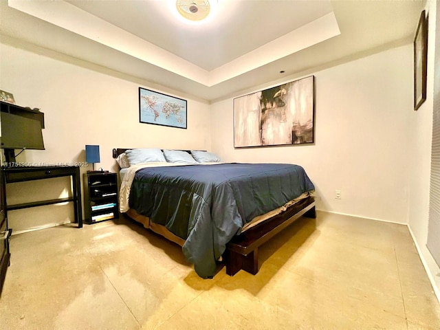 bedroom featuring a tray ceiling and baseboards