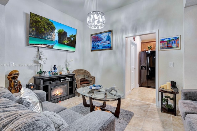 living area featuring a glass covered fireplace, light tile patterned floors, and an inviting chandelier