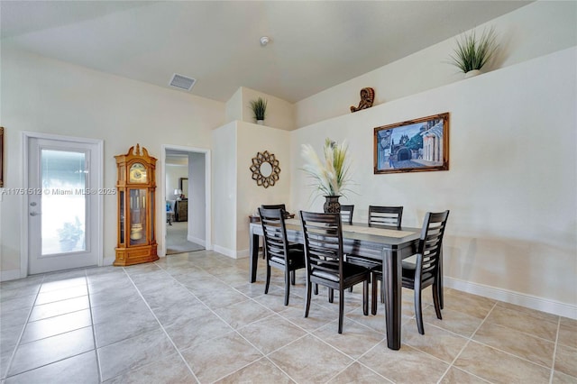 dining room with visible vents, vaulted ceiling, baseboards, and light tile patterned floors