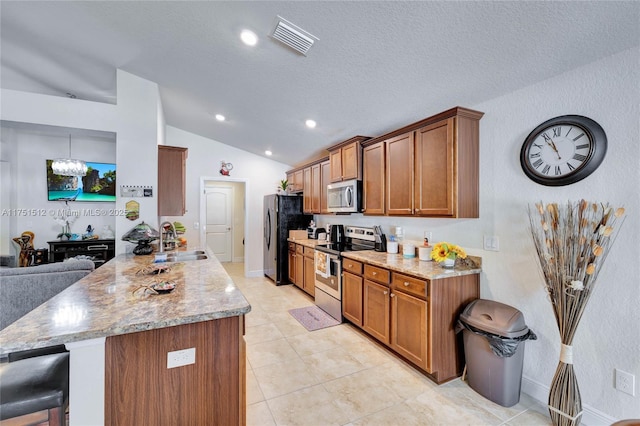 kitchen with brown cabinetry, visible vents, stainless steel appliances, and a sink