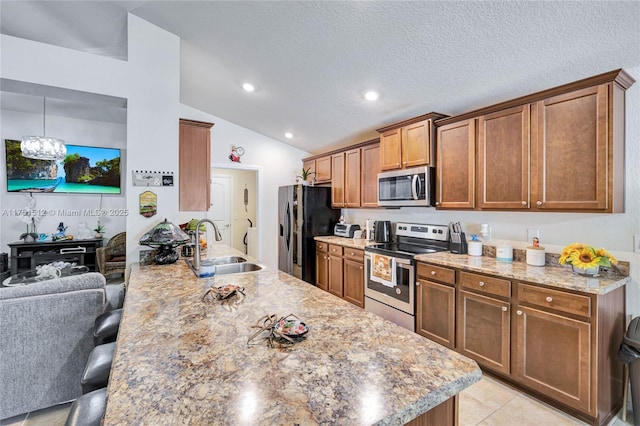 kitchen with appliances with stainless steel finishes, brown cabinets, a sink, and a breakfast bar area