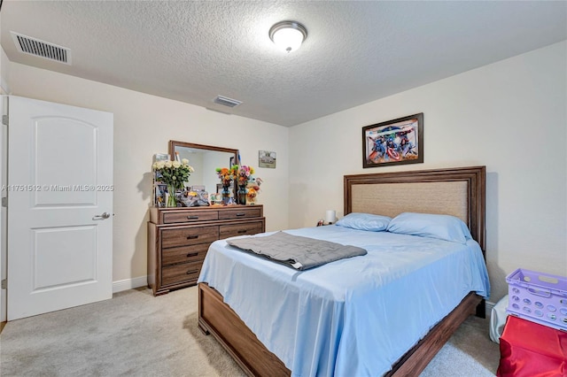 bedroom with baseboards, visible vents, light carpet, and a textured ceiling