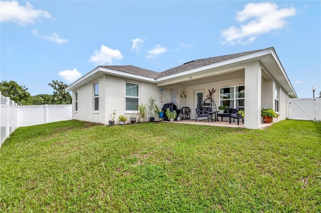 back of house featuring a patio, a fenced backyard, a yard, a gate, and stucco siding