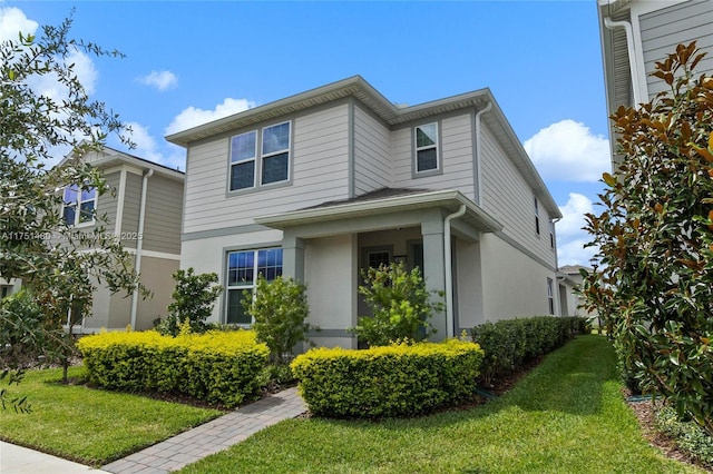 traditional-style home featuring a front lawn and stucco siding