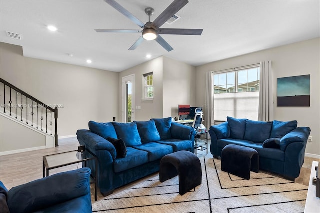 living area with stairway, baseboards, visible vents, and light wood-style flooring