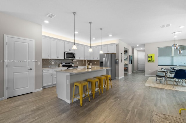 kitchen with visible vents, a center island with sink, appliances with stainless steel finishes, and white cabinets