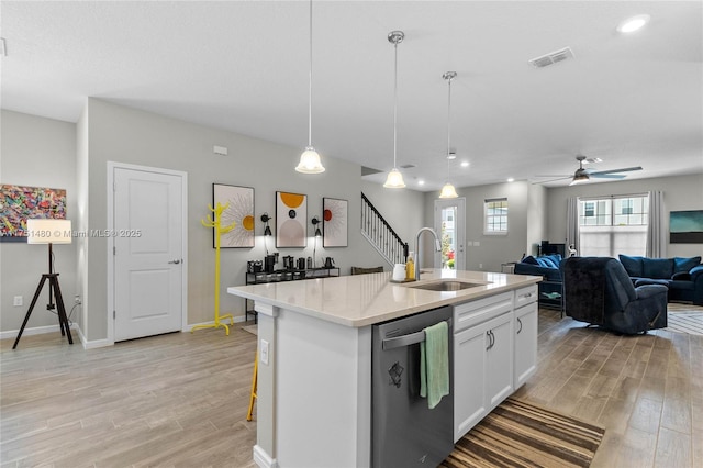 kitchen featuring white cabinets, open floor plan, light countertops, dishwasher, and a center island with sink