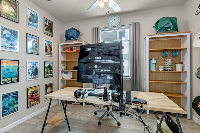 office space with light wood-style floors, ceiling fan, and baseboards