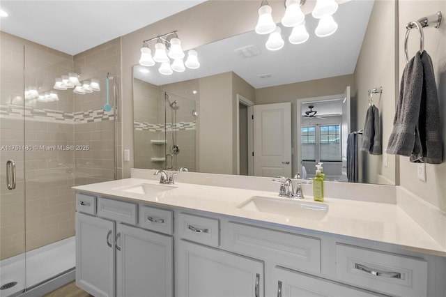 full bathroom featuring double vanity, a stall shower, ceiling fan, and a sink