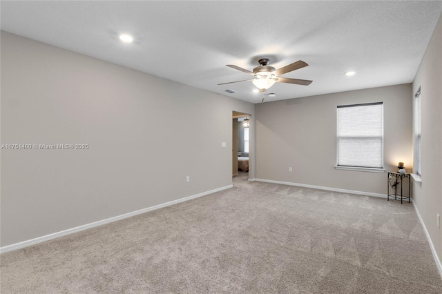 spare room featuring a ceiling fan, light carpet, visible vents, and baseboards