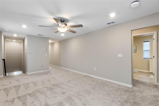 spare room featuring light carpet, baseboards, visible vents, and ceiling fan