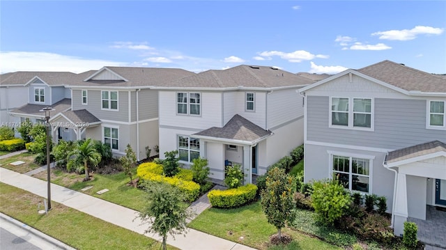 multi unit property featuring a residential view, roof with shingles, and a front yard