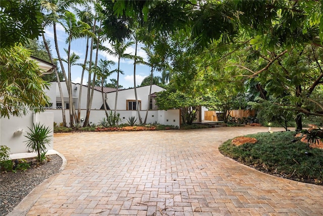 exterior space with fence, decorative driveway, and stucco siding