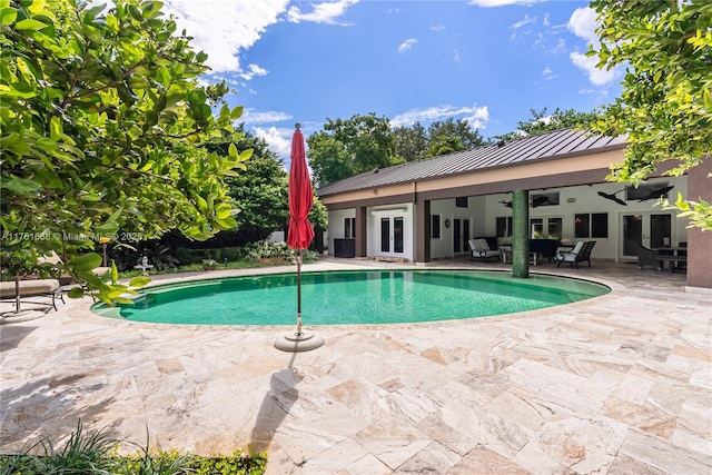 outdoor pool with ceiling fan, a patio, and french doors