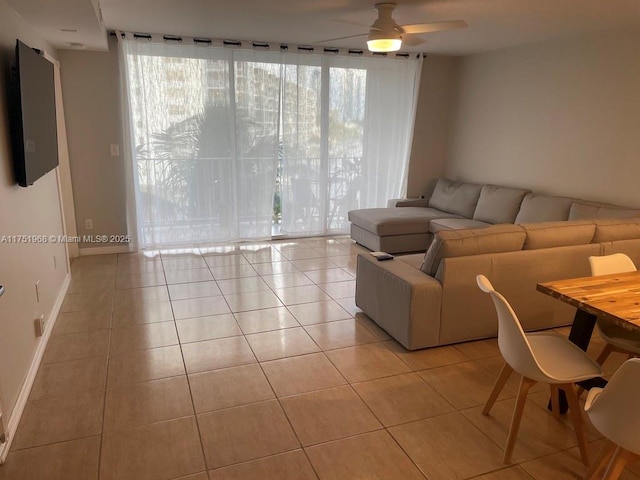 living area featuring a ceiling fan, light tile patterned flooring, and baseboards