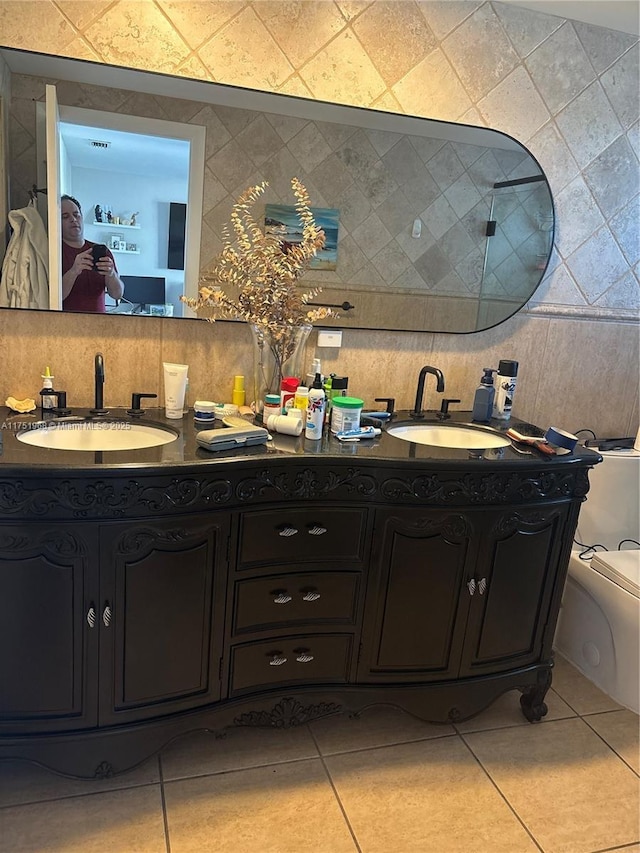 full bath featuring toilet, tile patterned flooring, tile walls, and a sink